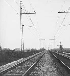 886036 Gezicht op een geëlektrificeerde spoorlijn met vakwerkmasten, mogelijk bij Lisse. Rechts op de achtergrond een ...